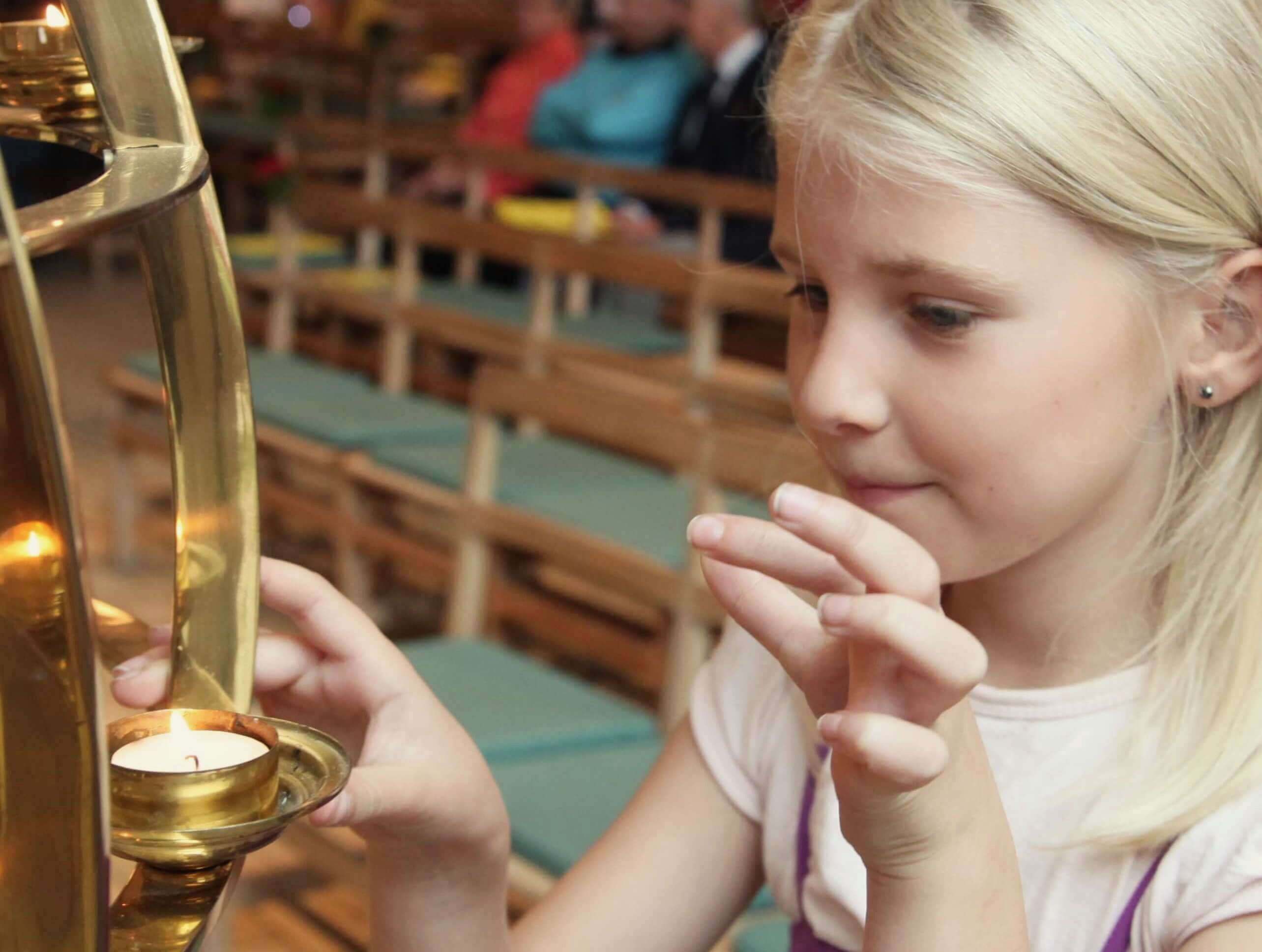 Ein junges Mädchen zündet eine Kerze in der Kirche an.